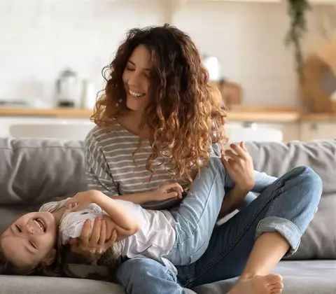 Mama scherzt auf Couch mit Kind